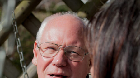 Older man sat in a park talking to a lady