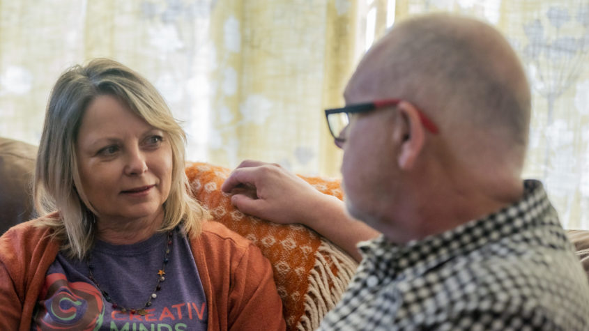 A lady talking to a man whilst sat on the sofa