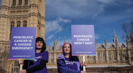 two ladies holding signs about pancreatic cancer