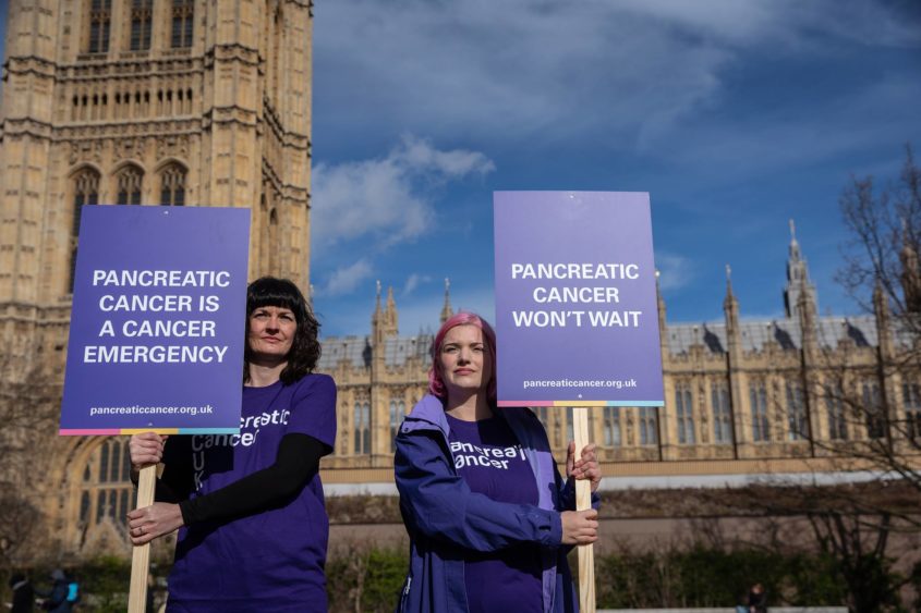 two ladies holding signs about pancreatic cancer