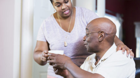 Woman giving an older man a hot drink