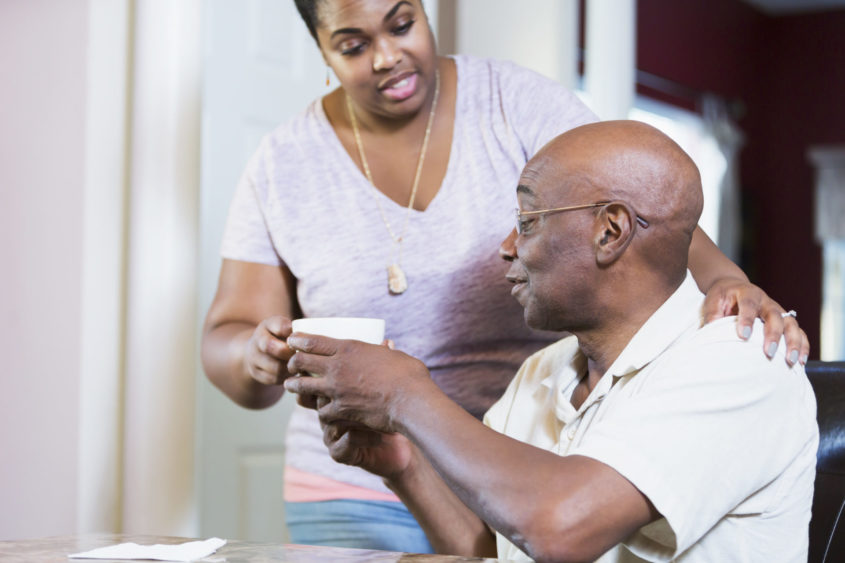 Woman giving an older man a hot drink