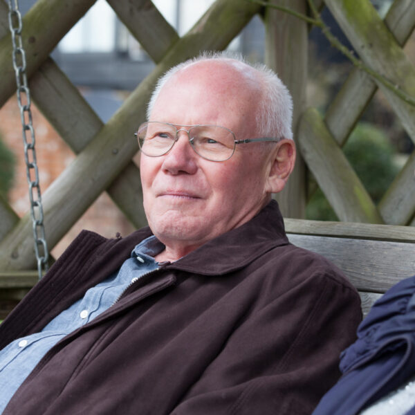 Older man sat on a park bench with a female