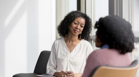 Mature counselor listens compassionately to unrecognizable female client