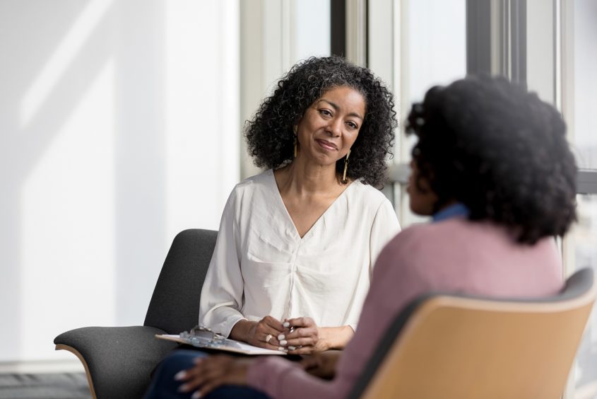 Mature counselor listens compassionately to unrecognizable female client