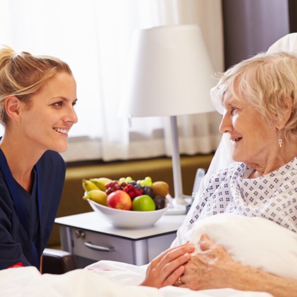 Nurse talking to older female patient in a hospital bed