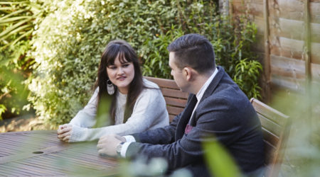 Man and lady sat in the garden at a table