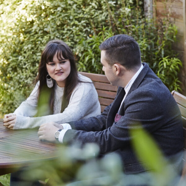 Man and lady sat in the garden at a table
