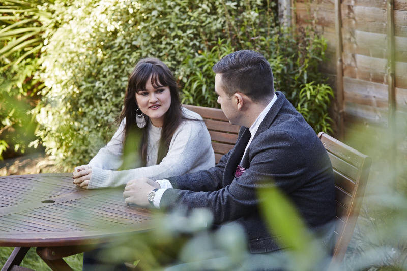 Man and lady sat in the garden at a table