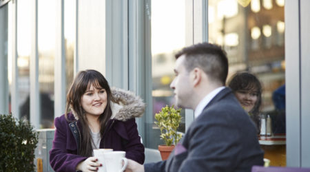 Man and lady sat outside having a coffee