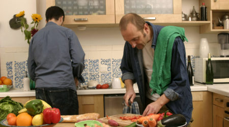 Man prepares dinner in his kitchen, chopping vegetables.