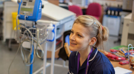 A nurse talking to someone in a hospital setting.