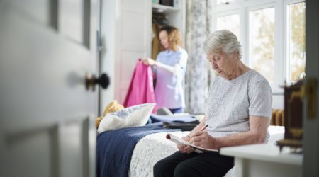 Woman sitting on bed writing in her notepad