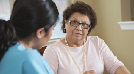 Senior Hispanic woman talking with home healthcare worker