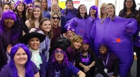 Group of PCUK workers all smiling and dressed in purple