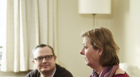 A man and lady talking in the front room, lady holding a cup of tea