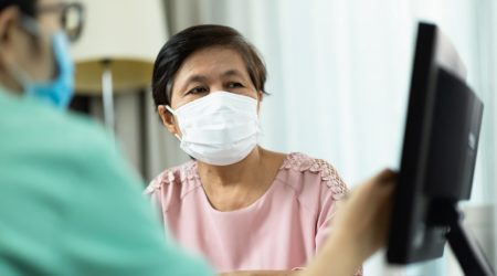 Woman wearing a face covering talks to a doctor