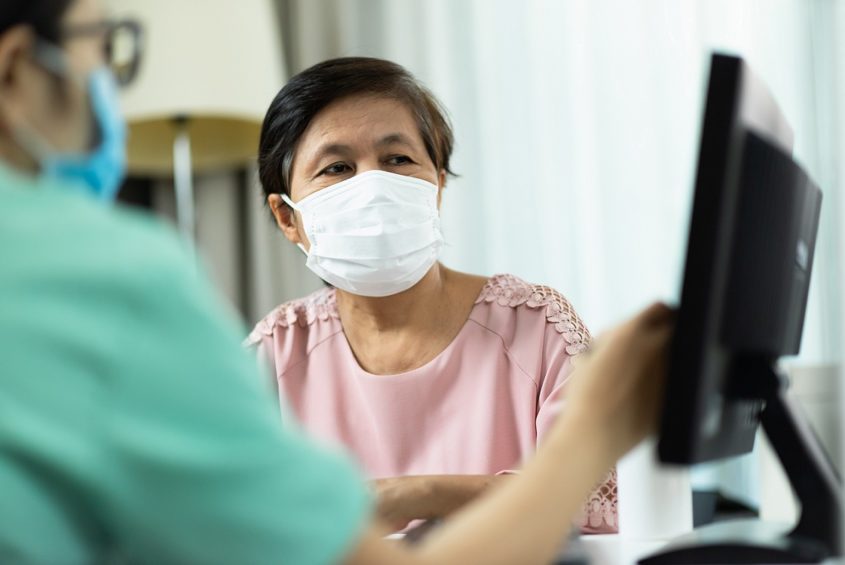 Woman wearing a face covering talks to a doctor