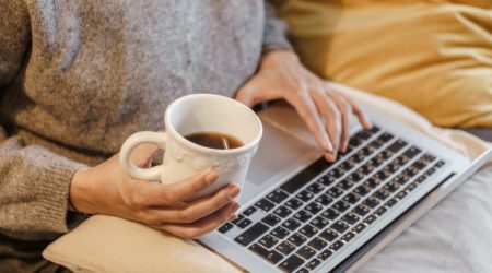 Lady with her laptop on her lap, holding a cup of tea