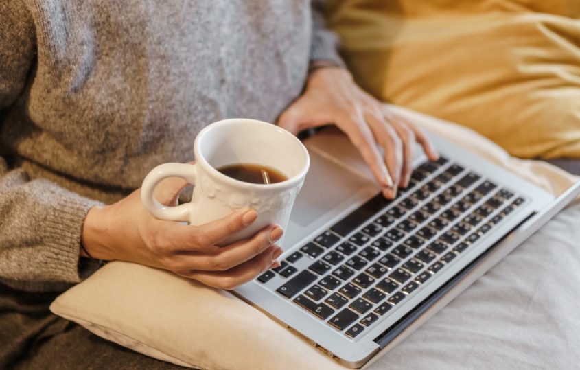Lady with her laptop on her lap, holding a cup of tea