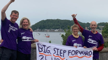 Four people holding a fabric flag for pancreatic cancer UK