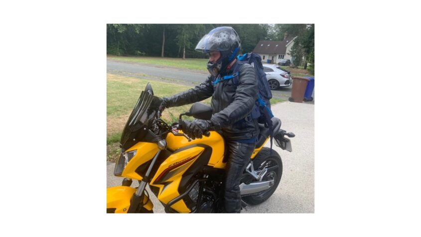 Man sitting on bright yellow motorbike wearing biking leathers and a helmet