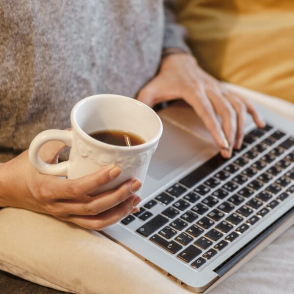 Someone on their laptop holding a cup of tea