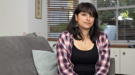 Mahika sitting in her living room looking to camera.