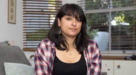 Mihika sitting in her livingroom looking directly at the camera.