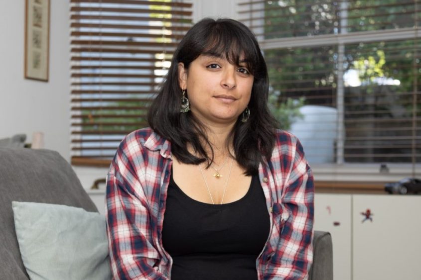 Mihika sitting in her livingroom looking directly at the camera.