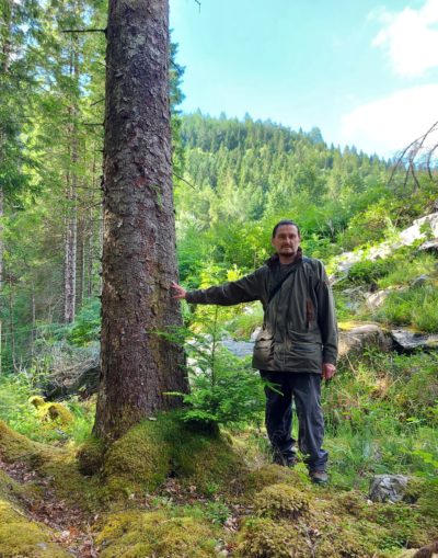 Ash poses in his green jacket in a Scottish landscape in summer