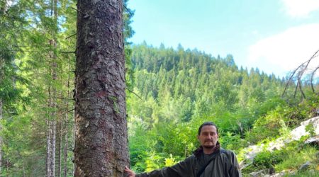 Ash poses in his green jacket in a Scottish landscape in summer