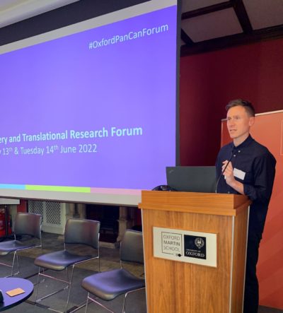 Pancreatic Cancer UK's Head of Research, Chris Macdonald standing at a lectern presenting at the Discovery and Translational Research Forum
