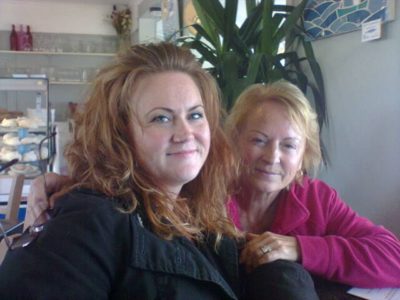 Two women pose happily for a photo in a cafe.