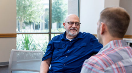 Mature adult father listens attentively to unrecognizable mid adult son