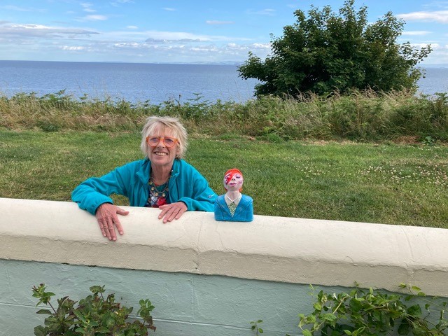 Jane Travers leaning against a wall next to one of her sculptures