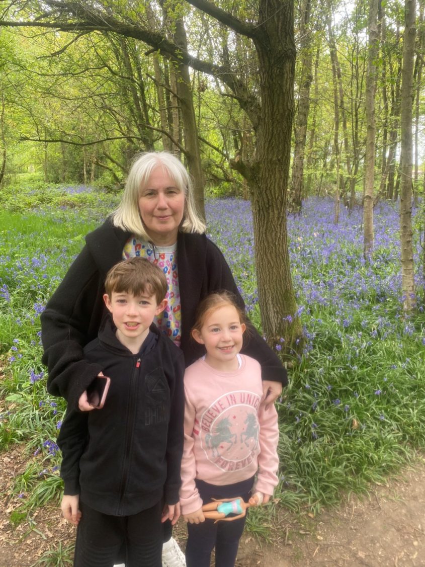 Becki stands with her children, Jacob and Georgie in the woods on a family day out