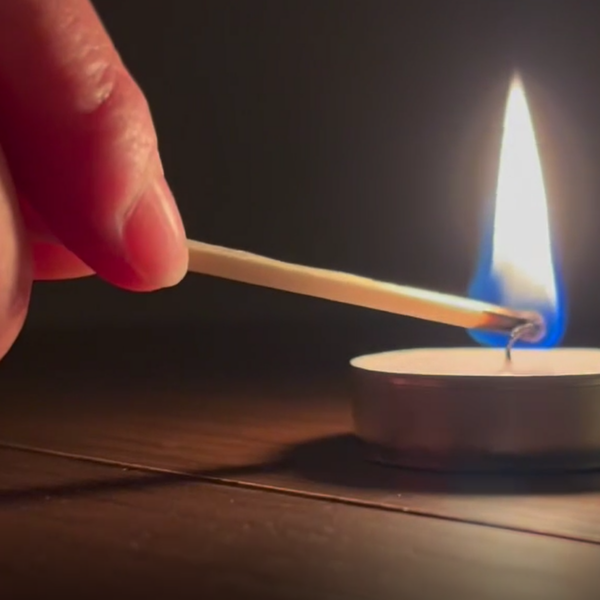 Light a candle in memory - a hand lighting a candle with a match