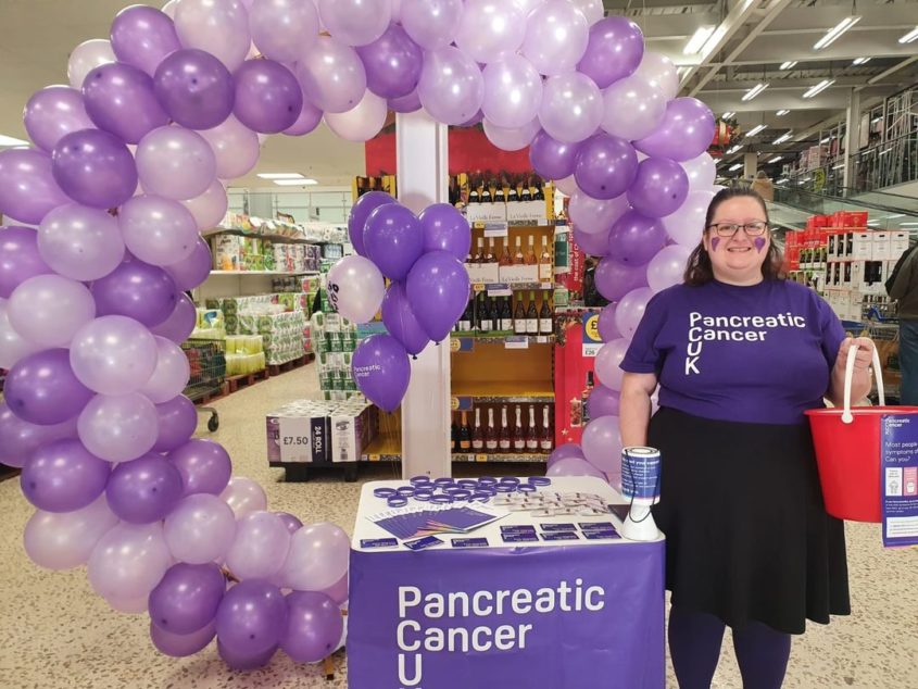 Volunteer smiling with collection bucket raising awareness for PCUK