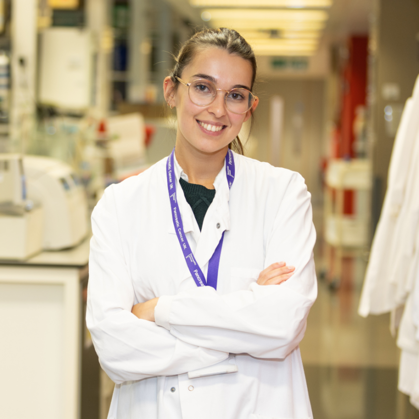 A woman standing in a lab coat in a research lab - Pancreatic cancer UK