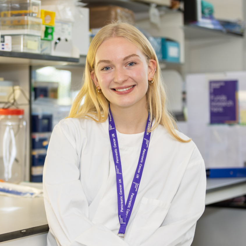 A woman standing in a lab coat in a research lab - PCUK - Charlotte