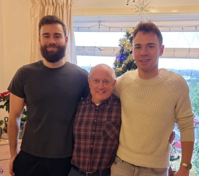 Andy standing in between his two sons, looking to camera and smiling