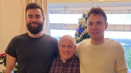 Andy standing in between his two sons, looking to camera and smiling