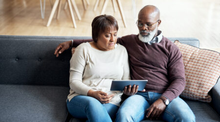 A couple sat on the sofa using a digital tablet