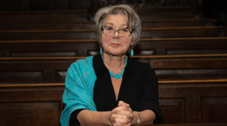 Actor Barbara Flynn sits on a pew wearing a turquoise shawl prior to our Carol Concert