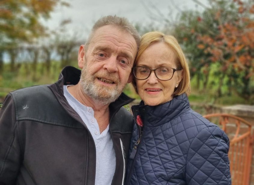 A middle-aged man & woman smile for the camera on a county walk