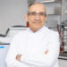 Professor George Hanna standing in a lab wearing a white lab coat with his arms crossed looking at camera