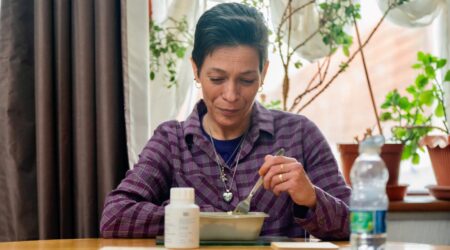 A woman sitting at a table eating from a bowl