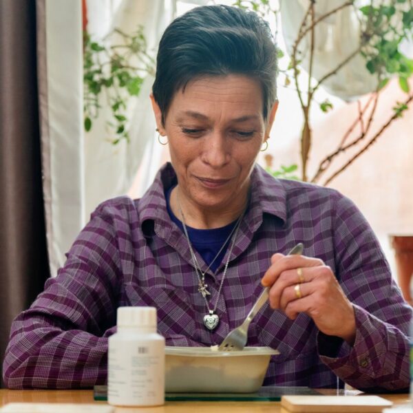 A woman sitting at a table eating from a bowl