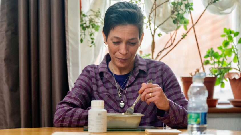 A woman sitting at a table eating from a bowl